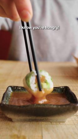 Sushi en train d'être trempé dans une sauce dans un restaurant japonais à emporter à Lausanne.