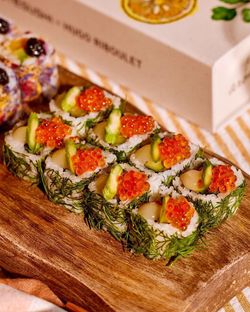 Sushis à emporter garnis d'avocat, œufs de poisson et herbes fraîches sur planche en bois