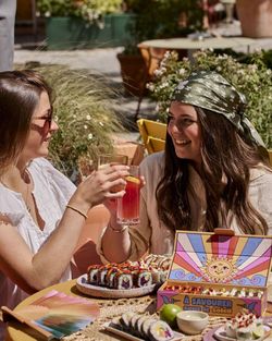 Deux femmes dégustent des sushis en terrasse avec boissons dans un cadre ensoleillé chez Côté Sushi Genève.
