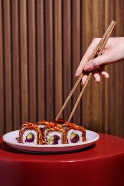 Baguettes prend un sushi de la plaque, sushi préparés dans un restaurant japonais à Genève.