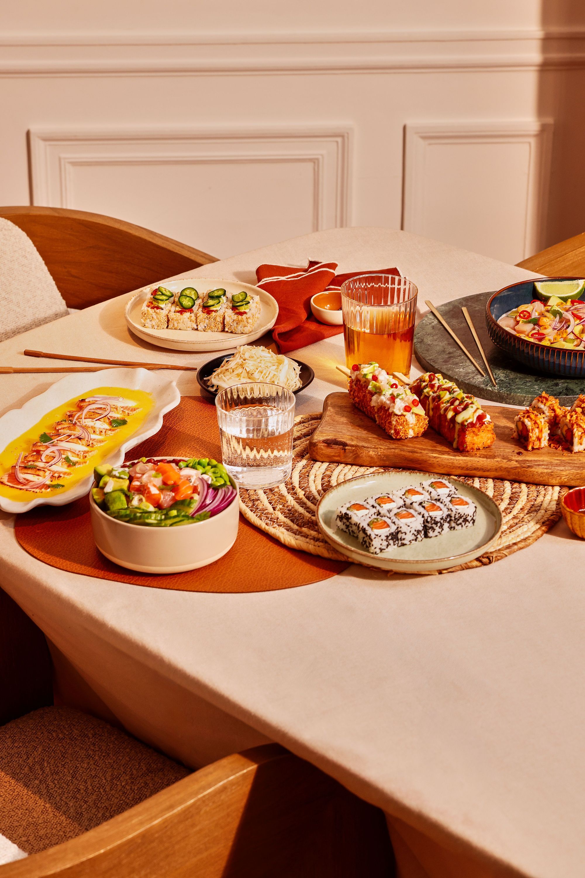 Assortiment coloré de sushi et plats japonais prêts à emporter sur une table avec boissons dans un restaurant japonais.