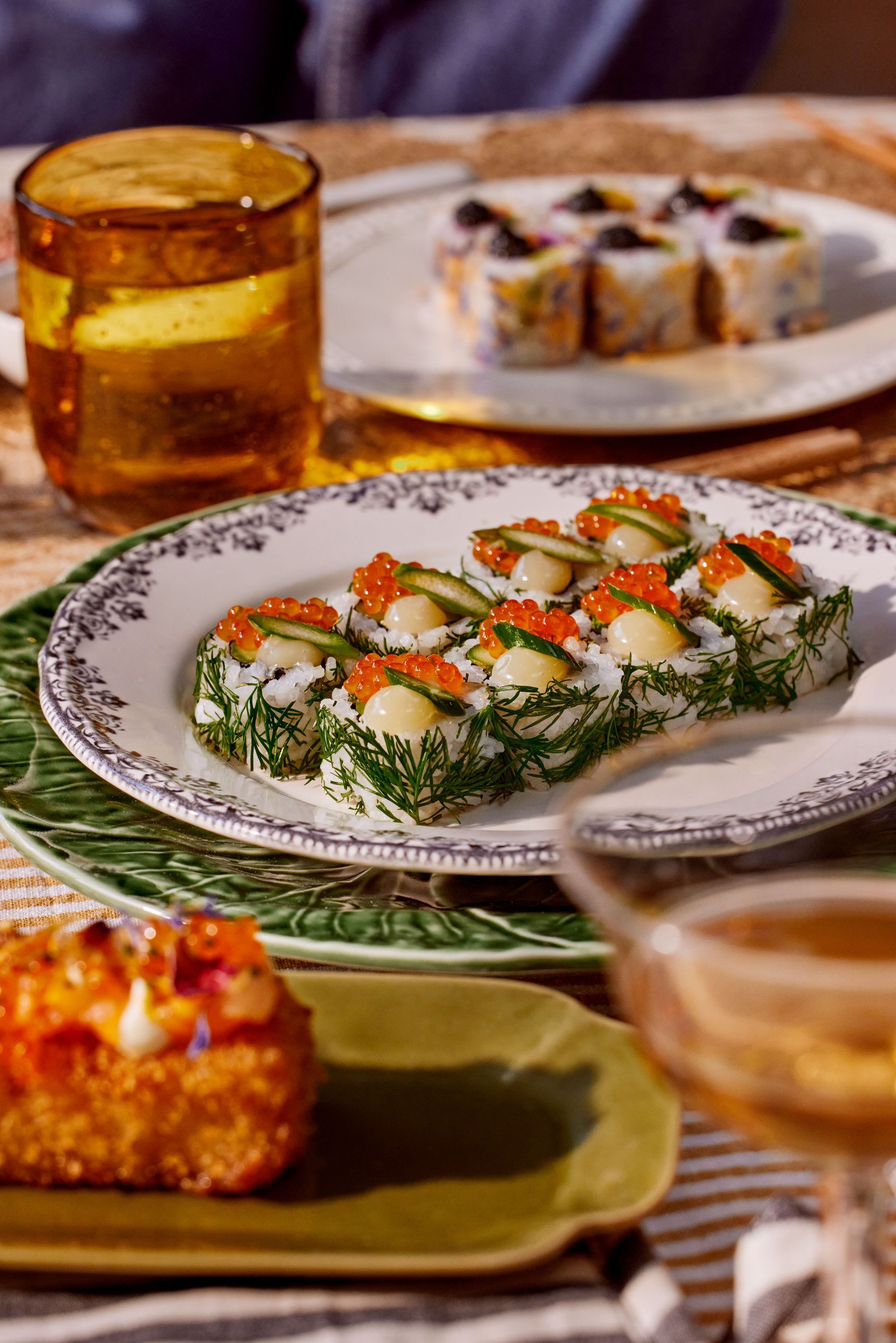 Plateau de sushis variés servis sur une table avec des verres et des assiettes décoratives.